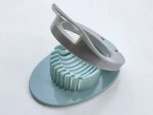 Gros plan détaillé d'un coupe-œufs de cuisine avec fils en acier inoxydable et base en plastique.