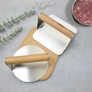 Stainless steel burger press and meat smasher with wooden handle for kitchen cooking.