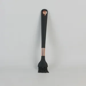 Silicone kitchen basting brush detail close-up, black handle with rose gold accent, baking tool.
