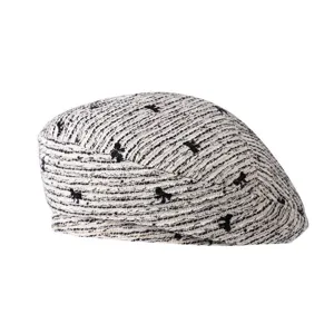 Vue détaillée d'un béret en tweed élégant avec un motif de nœud noir chic et texture douce.
