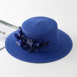 Detailaufnahme des eleganten blauen Strohhutes mit Stoffblumen und funkelnden Strasssteinen.