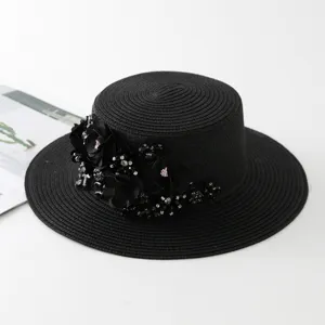 Detailansicht eines eleganten schwarzen Strohhutes mit floralen Verzierungen und Pailletten.