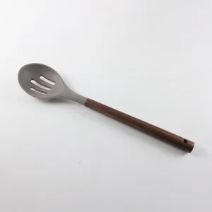 Écumoire en silicone avec manche en bois de noyer résistant, ustensile de cuisine détail.