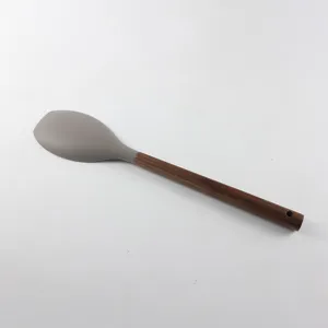 Détail de cuillère de cuisine en silicone, manche en bois avec trou de suspension.