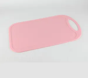 Pink plastic cutting board with non-slip handle, durable kitchen tool for chopping fruit.