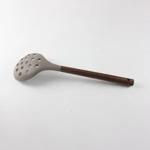 Vue détaillée d'une écumoire en silicone gris avec manche en bois sombre, outil de cuisine idéal.
