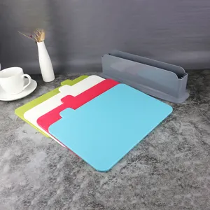 Plastic cutting board set detail showing four colorful boards and storage stand on dark surface