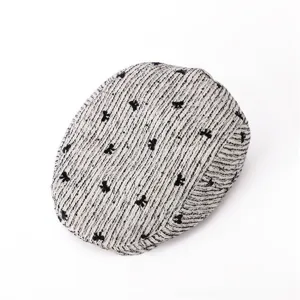 Casquette plate en tweed texturé avec motifs noirs, style rétro classique détail.