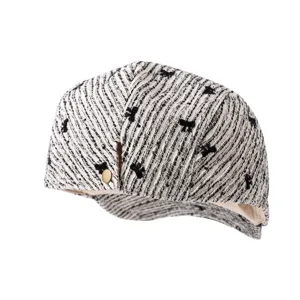 Vue détaillée du chapeau bob en tweed noir et blanc avec bouton métal et motif de nœud.