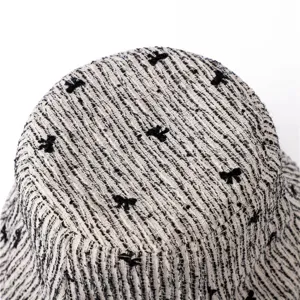 Gros plan détail du chapeau bob en tweed noir et blanc avec motif de nœud tissé.