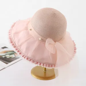 Detailed view of women pink organza sun hat with elegant pearls and bow beach wear.
