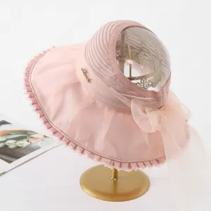 Elegant pink sun hat with transparent crown and large organza ruffle brim for beach vacation.