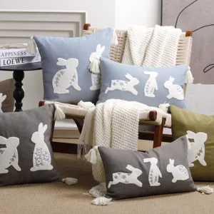 Detailed view of textured linen throw pillows featuring cute embroidered white bunnies and tassels.
