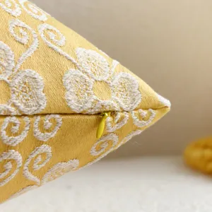 Detail shot of a yellow jacquard throw pillow cover with floral pattern and hidden zipper.