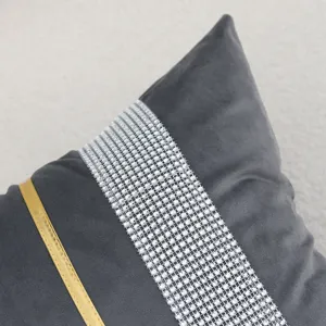 Close-up view of grey velvet pillow cover featuring rhinestone band and gold stripe detail.