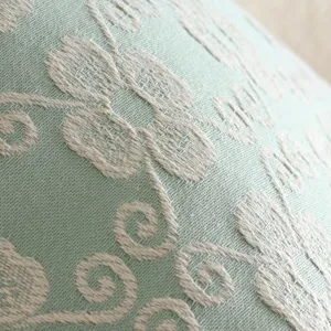 Close-up detail of light green embroidered floral jacquard cushion cover texture and pattern