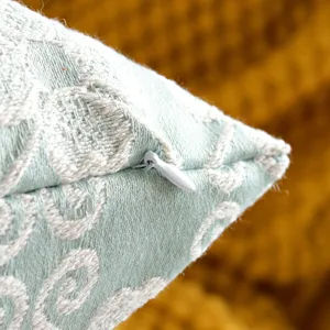 Close-up of light green jacquard cushion cover zipper and fine woven fabric texture.
