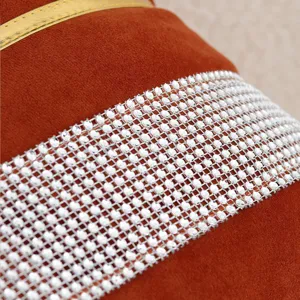 Close-up detail of luxury velvet cushion cover featuring sparkling rhinestone mesh and gold trim.