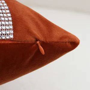 Close-up of rust orange velvet cushion cover featuring rhinestone trim and hidden zipper.