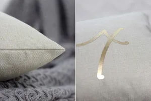 Detailed close-up view of the elegant beige cushion cover featuring a stylish gold foil letter.