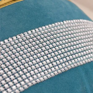 Close-up of velvet cushion cover with sparkling rhinestone mesh trim and gold stripe.