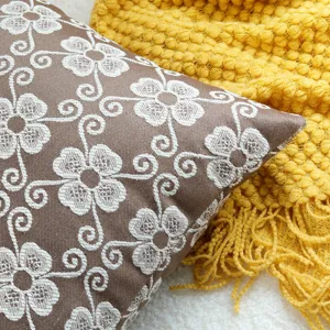 Brown jacquard throw pillow cover with white floral pattern, detailed view of textured cushion.