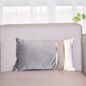 Velvet throw pillow detail showing modern two-tone spliced design and luxurious gold foil stripes.