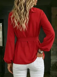 Detail view of the red long sleeve blouse featuring a ruffled collar and waist tie design.