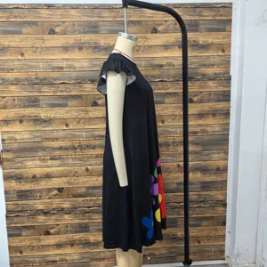 Side detail shot of a black sleeveless casual dress featuring colorful floral prints at the hem.