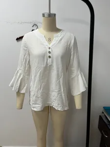 Detail view of the white linen blouse highlighting v-neck and elegant bell sleeves.