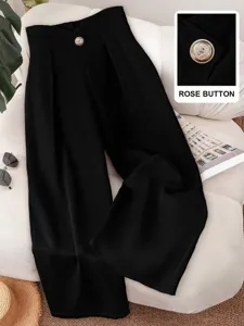 Close-up detail view of high-waisted black wide-leg trousers featuring a fine decorative button.
