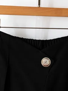 Detailed view of women's black wide leg trousers featuring a chic embossed gold metal button.