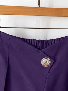 Close-up detail of purple high-waisted wide-leg trousers featuring asymmetrical crossover waist.