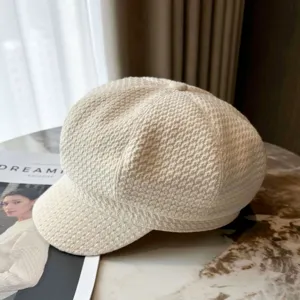 Close-up of a beige textured houndstooth newsboy cap in a stylish indoor setting