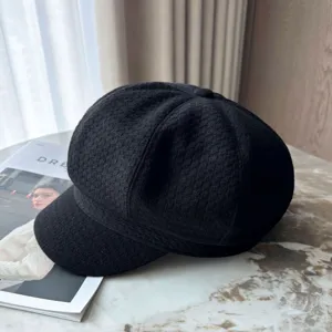 Close-up of a classic black textured octagonal newsboy cap displayed on a table