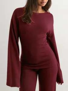 Gedetailleerd overzicht van de bordeauxrode top met lange uitlopende mouwen en broek.