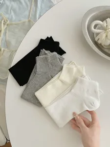 Detailed view of women's thin solid color sock covers in black, grey, white, and cream.