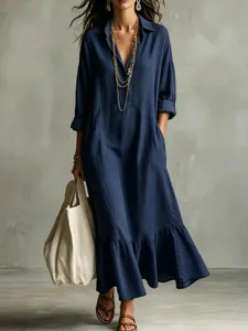 Close-up view of a navy blue long-sleeve loose shirt dress with a stylish ruffle hem.