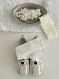 Close-up detail of white ribbed knit socks styled with silver shoes on aesthetic setting.