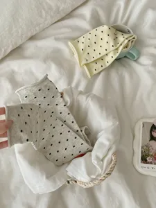 Close-up detail shot of cute polka dot mid-tube socks displayed neatly on cozy white bedding.