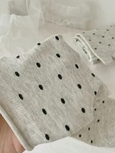 Close-up of grey split-toe socks with black dot pattern and ribbed texture detail.