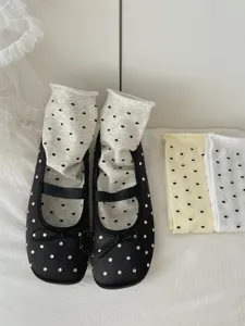 Close-up detail of black rhinestone flat shoes with polka dot socks, elegant daily wear style.