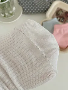 Gros plan de détails de chaussettes blanches en maille côtelée, texture douce et fin tissu.