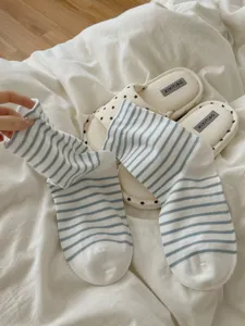 Primo piano dettagliato di calzini a tubo medio a righe blu e bianche su biancheria da letto.