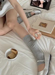 Close-up detail of grey ribbed stirrup leg warmers and ballet style socks on bed.