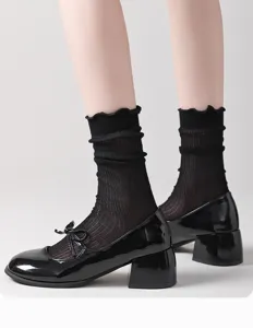 Primer plano de calcetines negros transparentes con volantes y un delicado borde ondulado.