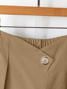 Close-up detail of women's casual trousers featuring an asymmetric waist and vintage button.