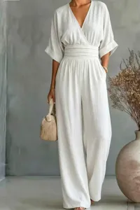 Close-up detail of a white V-neck short sleeve jumpsuit with banded waist and wide leg cut.