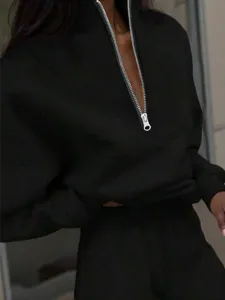 Black quarter-zip long sleeve sweatshirt detail view showing textured fabric and silver hardware.