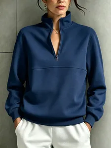 Close-up detail of a dark blue quarter-zip stand collar sweatshirt with ribbed hem.